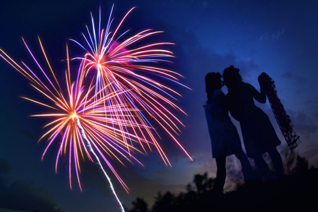 two girls standing watching fireworks on the 4th of July in the sky