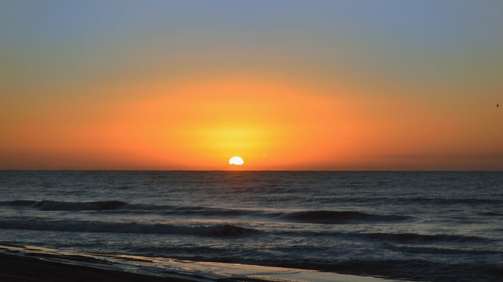 Dawn along the Atlantic Ocean shoreline in North Myrtle Beach, SC with a beautiful orange cast from the rising sun
