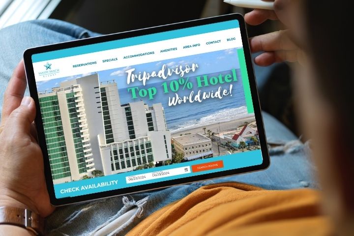 Man holding a tablet with Sandy Beach Oceanfront Resort pulled up to book a summer vacation today